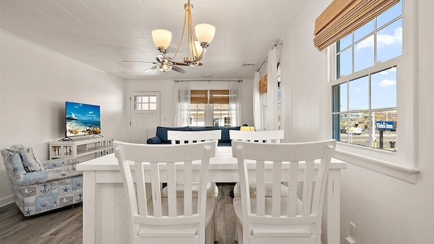 A white interior with a dining area, a TV, and a view of the outside. - Great Location for Family fun at Jolly Roger and Boardwalk! (Ocean City)