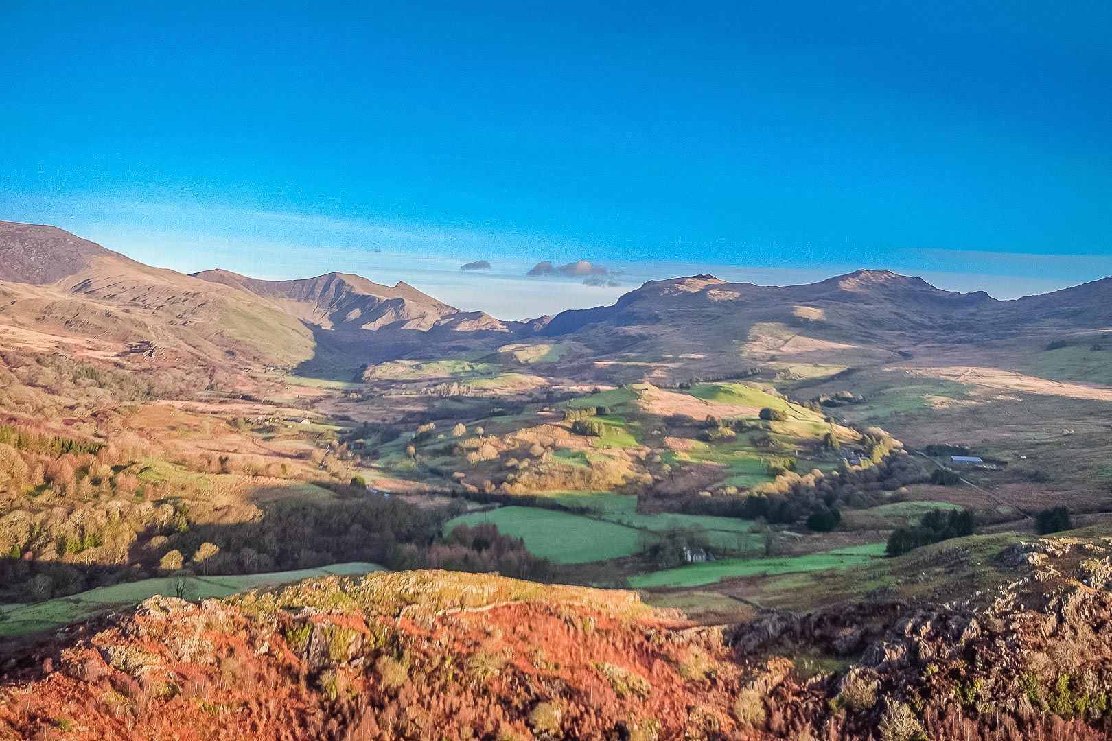 A panoramic view of a mountainous landscape with rolling hills and a valley.