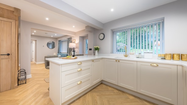 A modern kitchen with white cabinetry, a wooden door, and a window with blinds. - Beautifully Converted Workshop Close to the Beach | Gweithdy-Bronafon (Borth y Gest)