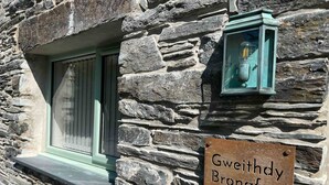 A stone building with a window and a sign reading 'Gweithdy Bronafon.' - Beautifully Converted Workshop Close to the Beach | Gweithdy-Bronafon (Borth y Gest)