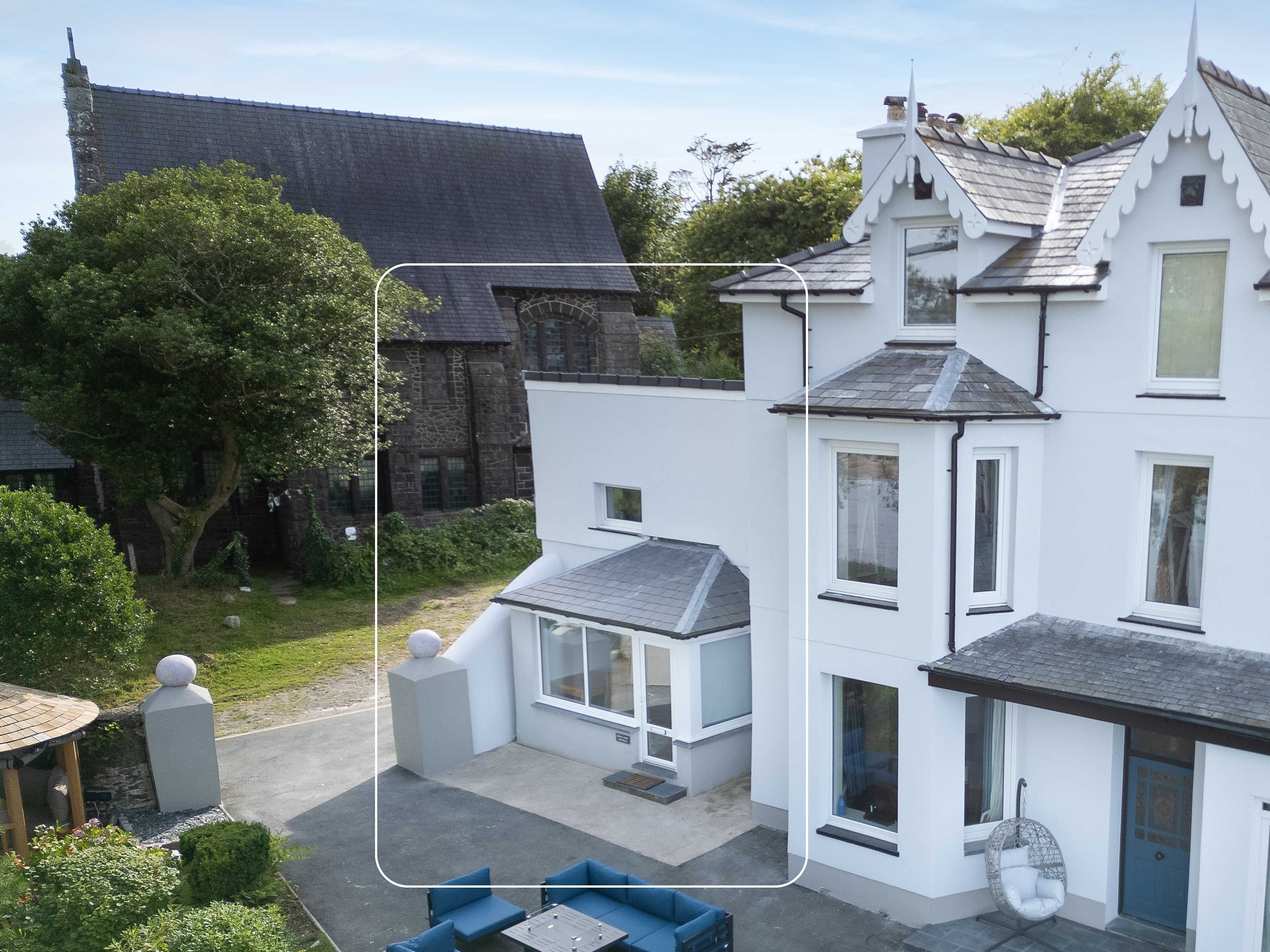 Une maison moderne dotée d’un patio, d’un fauteuil suspendu et d’un mur en pierre.