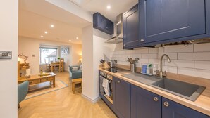 Een moderne keuken met blauwe kastjes, een roestvrijstalen spoelbak en een eethoek met houten meubilair.