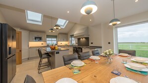 A modern kitchen with a dining area, skylights, and a view of the outdoors.