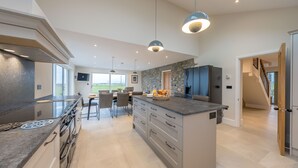 A modern kitchen with a central island, built-in appliances, and pendant lighting.
