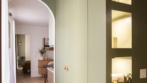 A hallway with a wooden floor, a white door with a small window, and a light fixture on the wall. - Appartement 2 chambre la fayette gare du nord - 4p (Paris)