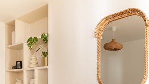 A bedroom with a bed, pillows, a shelf with decorative items, and a mirror. - Appartement 2 chambre la fayette gare du nord - 4p (Paris)