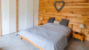 A bedroom with a wooden headboard, a bed with patterned bedding, bedside tables with lamps, and a wardrobe with sliding doors. - Chalet 'Le Ch'ti  Lecelles' with Private Terrace and Private Garden (Lecelles)