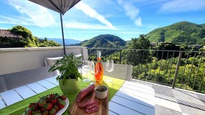 En balkon med et bord dækket til et måltid, en flaske og glas.