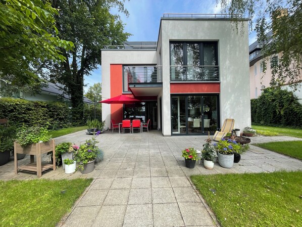 Un bâtiment moderne à deux étages doté d’un patio aménagé avec des espaces de détente en plein air et des plantes en pot.