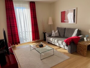 Un salon avec un canapé, une table basse en verre, une lampe et un tableau accroché au mur.