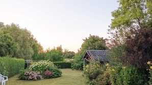 A garden with a small gazebo, neatly trimmed hedges, and a grassy lawn. - 6 Person Holiday Home in Samso (Samsø)