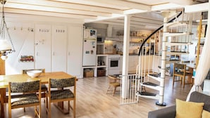 A spacious living area with a wooden dining table, chairs, a sofa, a staircase, and a kitchen in the background. - 6 Person Holiday Home in Samso (Samsø)
