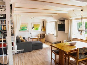 A cozy living room with a sofa, a dining table, and a bookshelf filled with books. - 6 Person Holiday Home in Samso (Samsø)