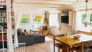 A cozy living room with a sofa, a dining table, and a bookshelf filled with books. - 6 Person Holiday Home in Samso (Samsø)