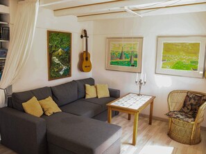 A living room with a sofa, a guitar, and framed artwork on the wall. - 6 Person Holiday Home in Samso (Samsø)