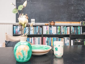 Une bibliothèque remplie de livres, un tableau noir et une petite figurine.