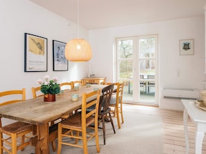 Un coin repas avec une table et des chaises en bois, un luminaire suspendu et des œuvres d’art encadrées accrochées aux murs.