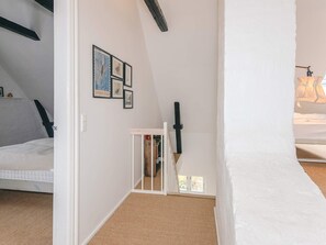 A bedroom with a sloped ceiling, a bed, a white wall with framed pictures, and a window. - 7 Person Holiday Home in Tim (Tim)