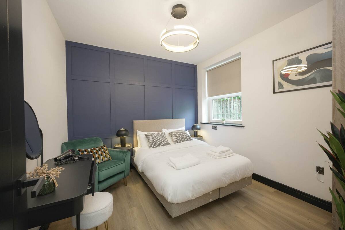 Ein modernes Schlafzimmer mit Bett, Nachttischen, Schreibtisch, Stuhl und Fenster.