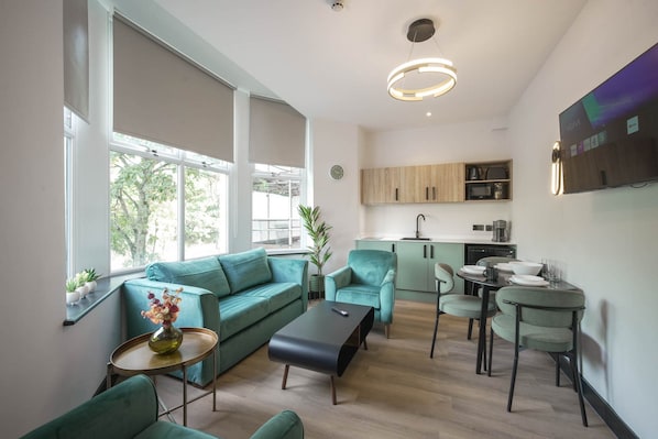 A modern living room with a sofa, armchair, coffee table, and a dining area with chairs and a table.
