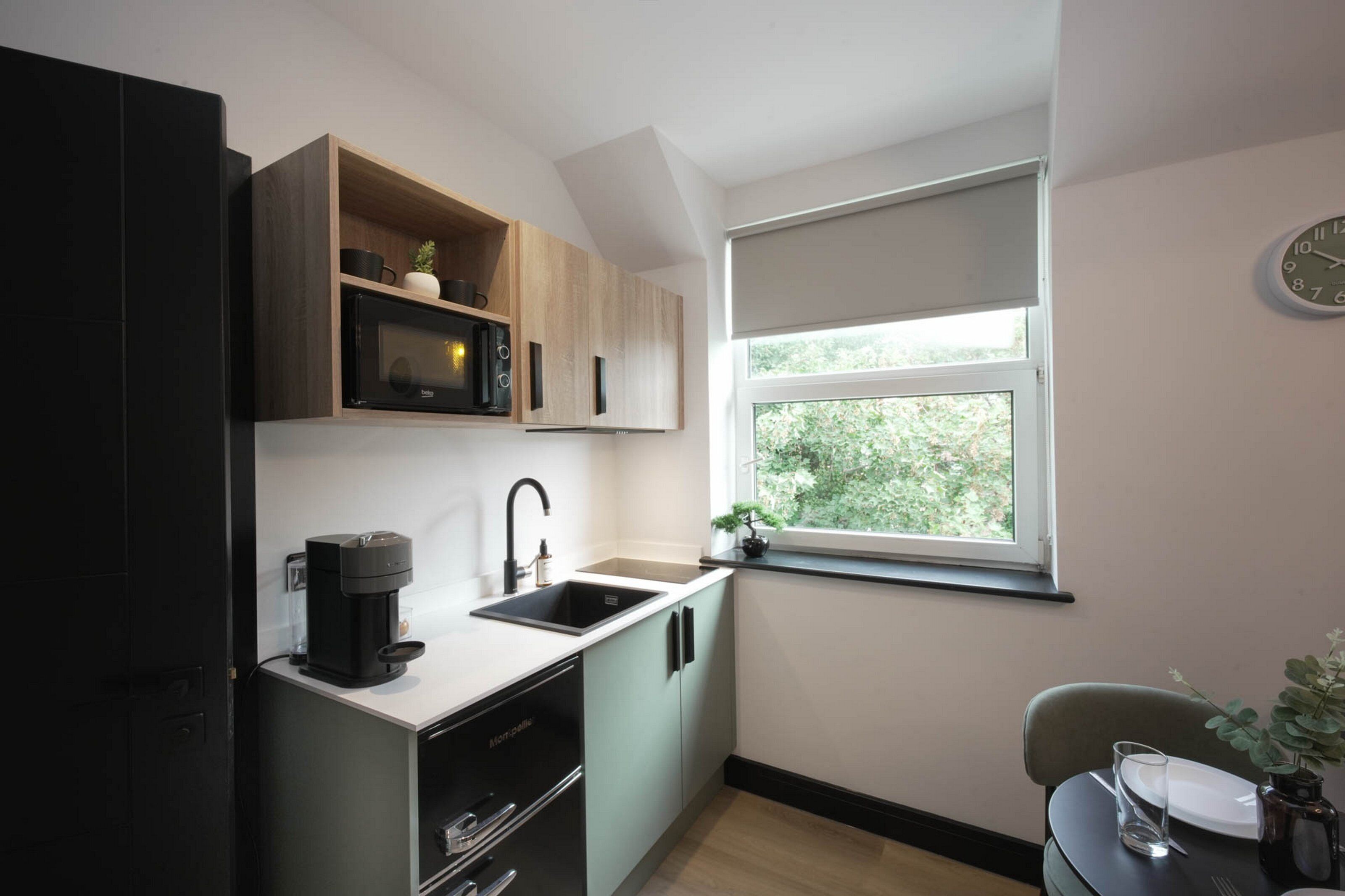 Cocina compacta con cafetera, pileta y ventana con vista a zonas verdes.