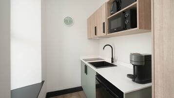 Una cocina moderna con una cafetera negra, un microondas y un lavabo.