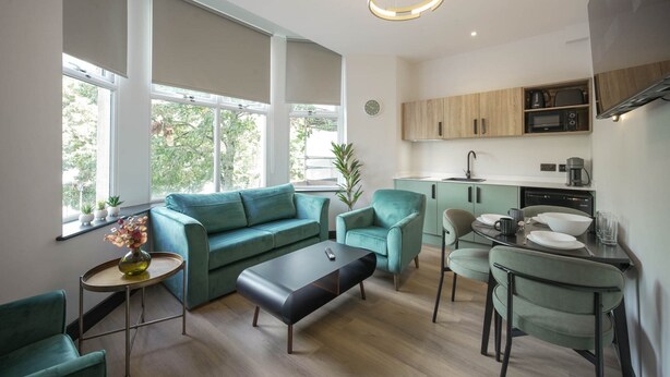 A modern kitchen with built-in appliances, a dining area with a table and chairs, and a living space with a sofa and coffee table. - The Sixty 19 Stylish Studios and Apt. (Cardiff)
