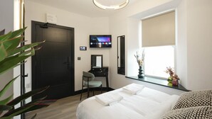 A hotel room with a bed, a desk, a chair, a TV, and a window with a view. - The Sixty 19 Stylish Studios and Apt. (Cardiff)