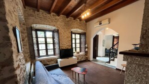 Une pièce aux murs de pierre, avec un canapé, une télévision et une petite table.