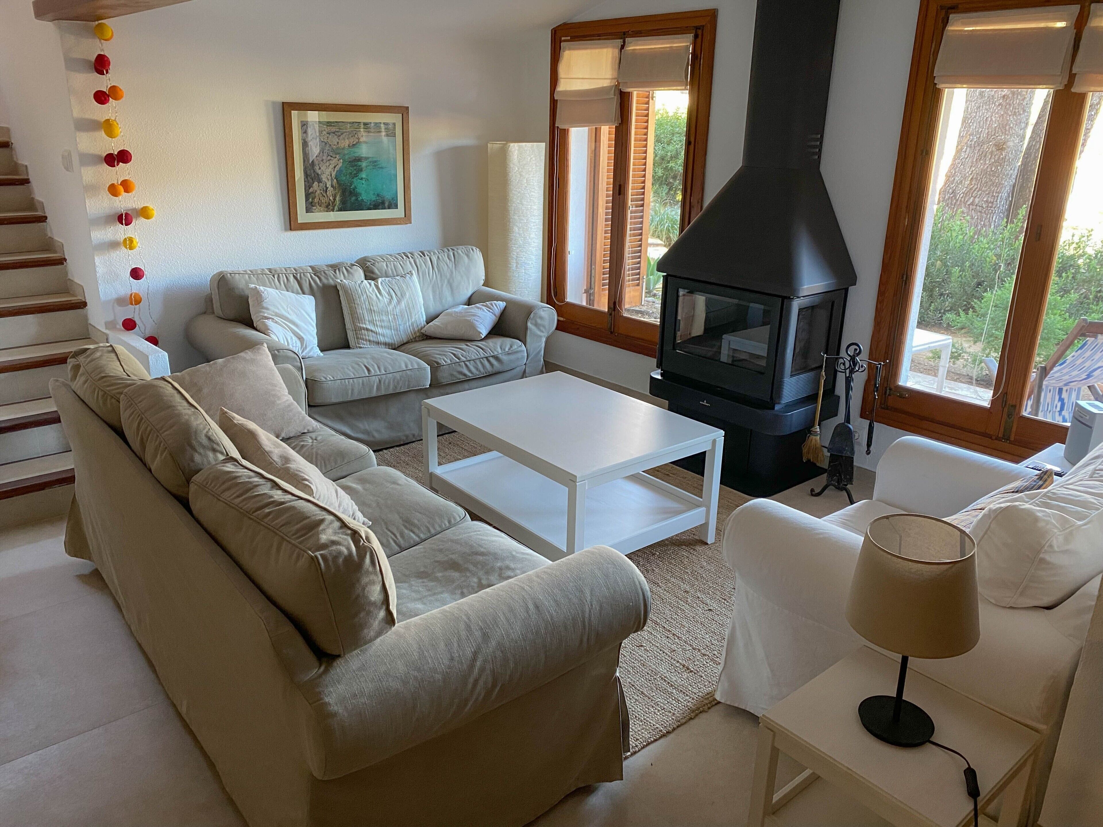 Un salon avec un canapé, une table basse blanche, une cheminée et un tableau au mur.