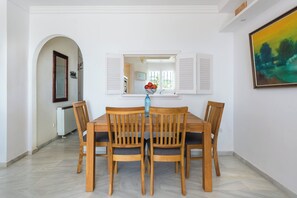 A dining area with a wooden table and chairs, a mirror, and a painting on the wall. - Jardines de Calahonda IX | Sea View & Pool (Mijas Costa)