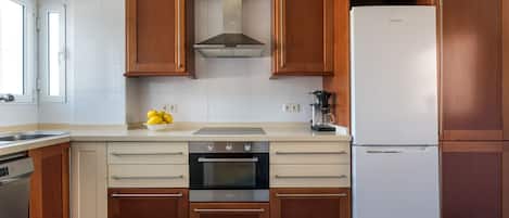 Cocina moderna con armarios de madera, horno de acero inoxidable, lavavajillas integrado y refrigerador blanco.