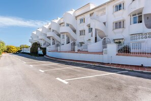 A white building with multiple balconies and a parking lot in front. - Jardines de Calahonda IX | Sea View & Pool (Mijas Costa)