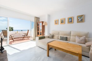 A living room with a sofa, a coffee table, and a balcony with a table and chairs.