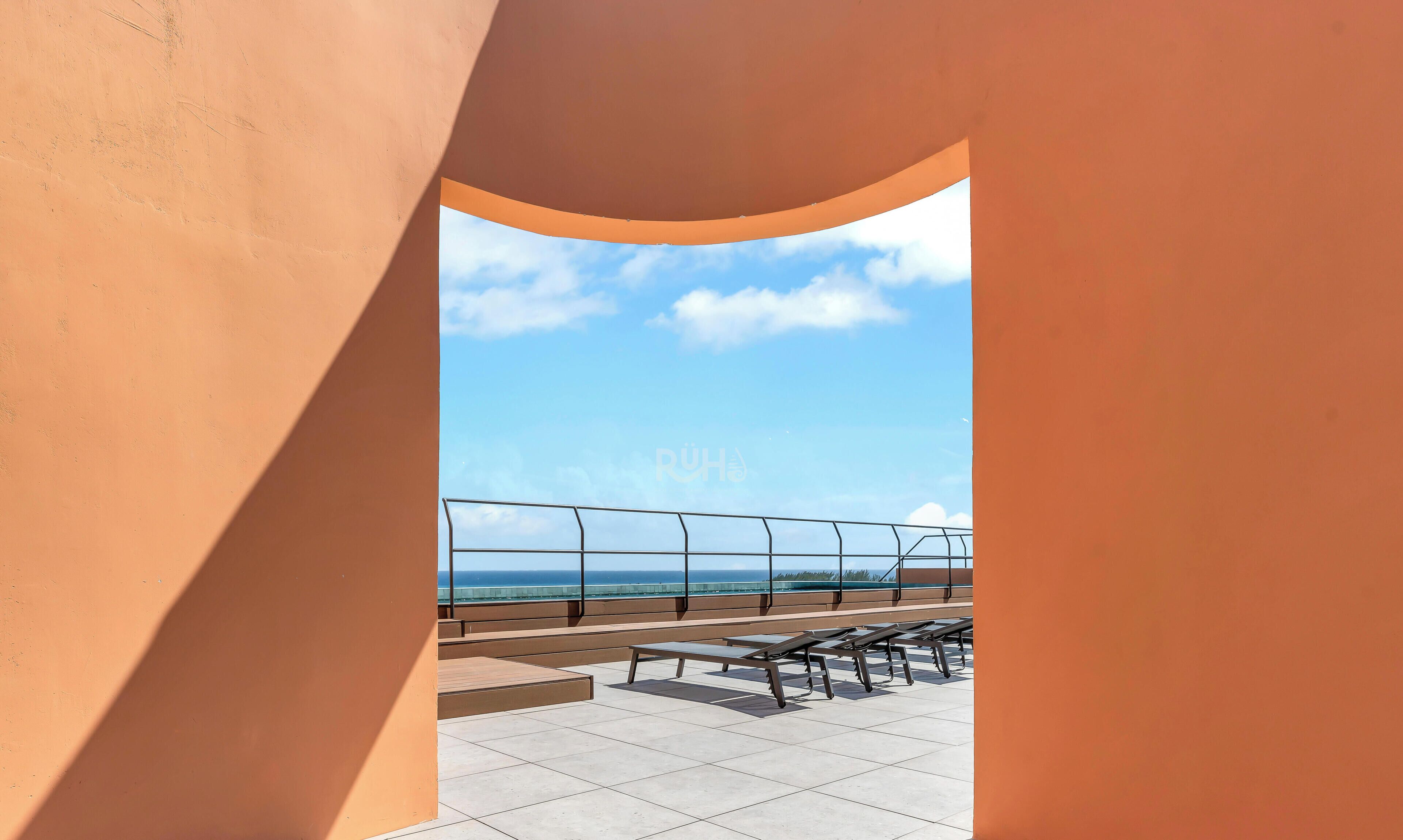 A terrace with a view of the sea, metal railings, and a few benches.