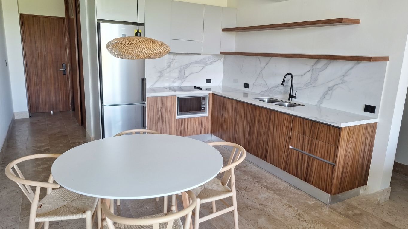 A modern kitchen with a round dining table and chairs, a built-in oven, and a microwave.