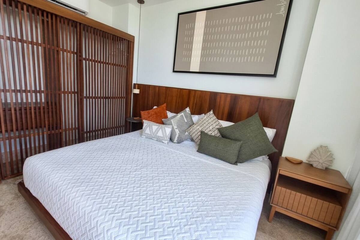 Ein Schlafzimmer mit Bett, Holz-Kopfstütze und Wandbild.