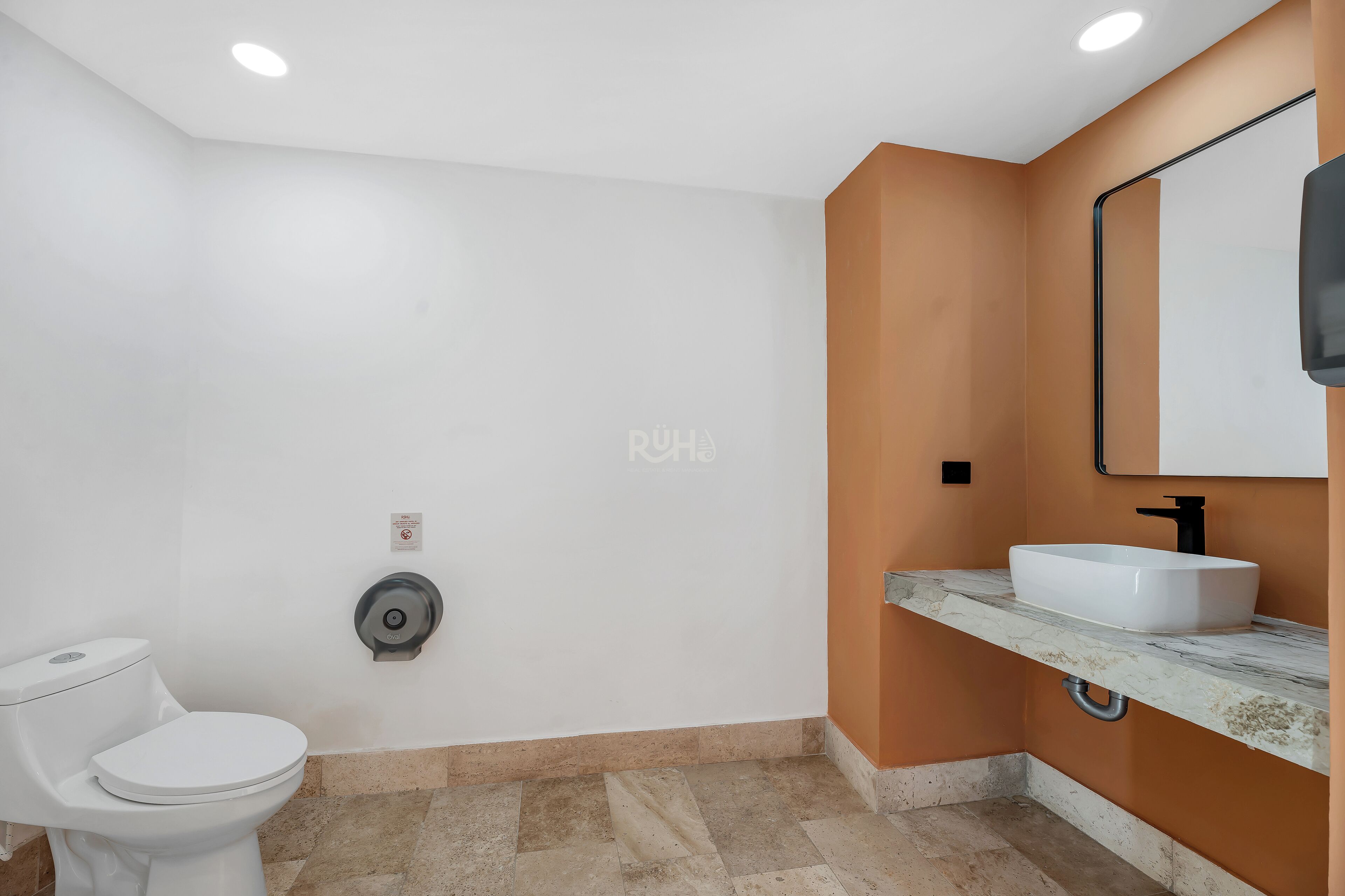 A bathroom with a toilet, a sink, and a mirror.