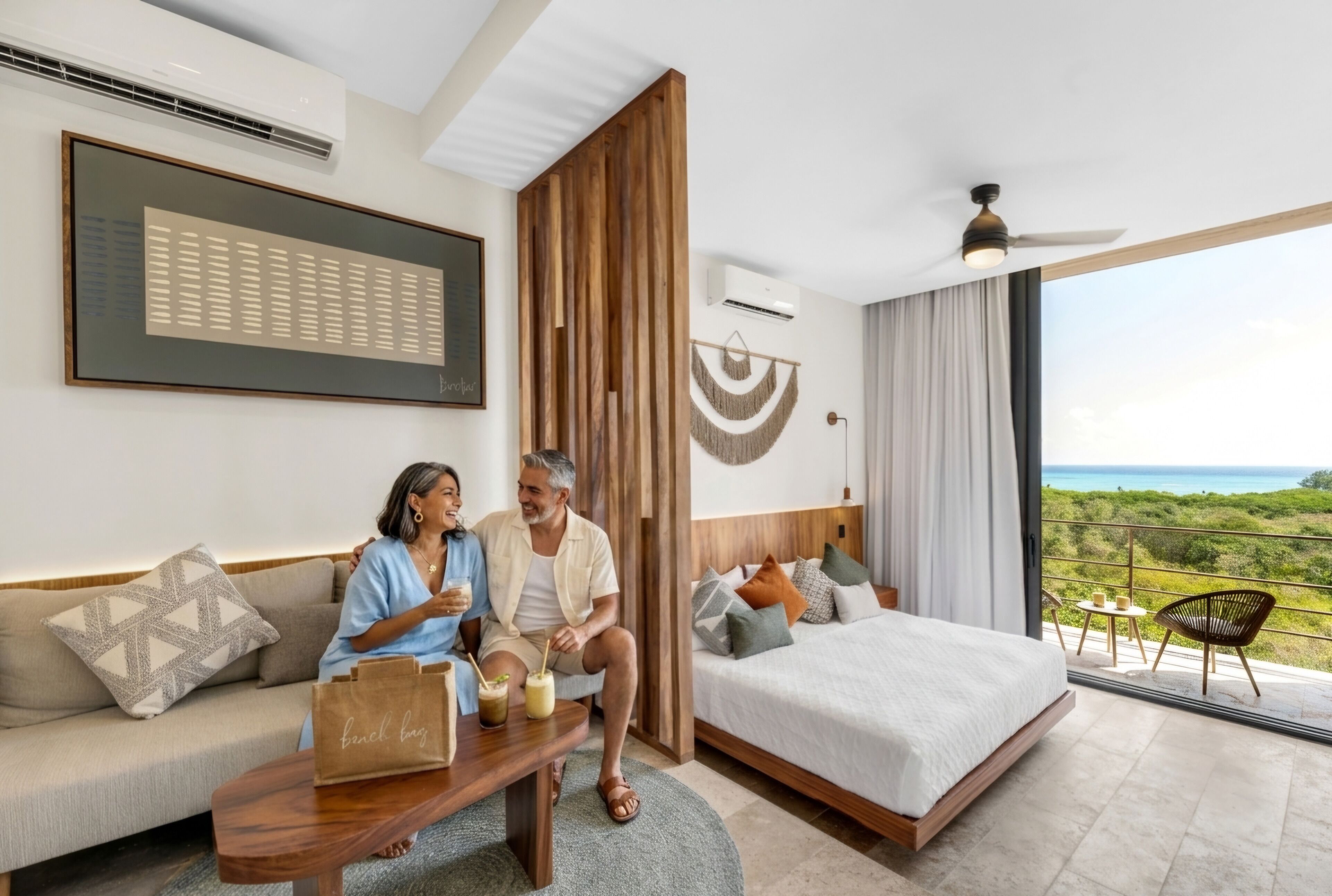 Ein Hotelzimmer mit Bett, Sofa, Couchtisch, Blick ins Freie und Deckenventilator.