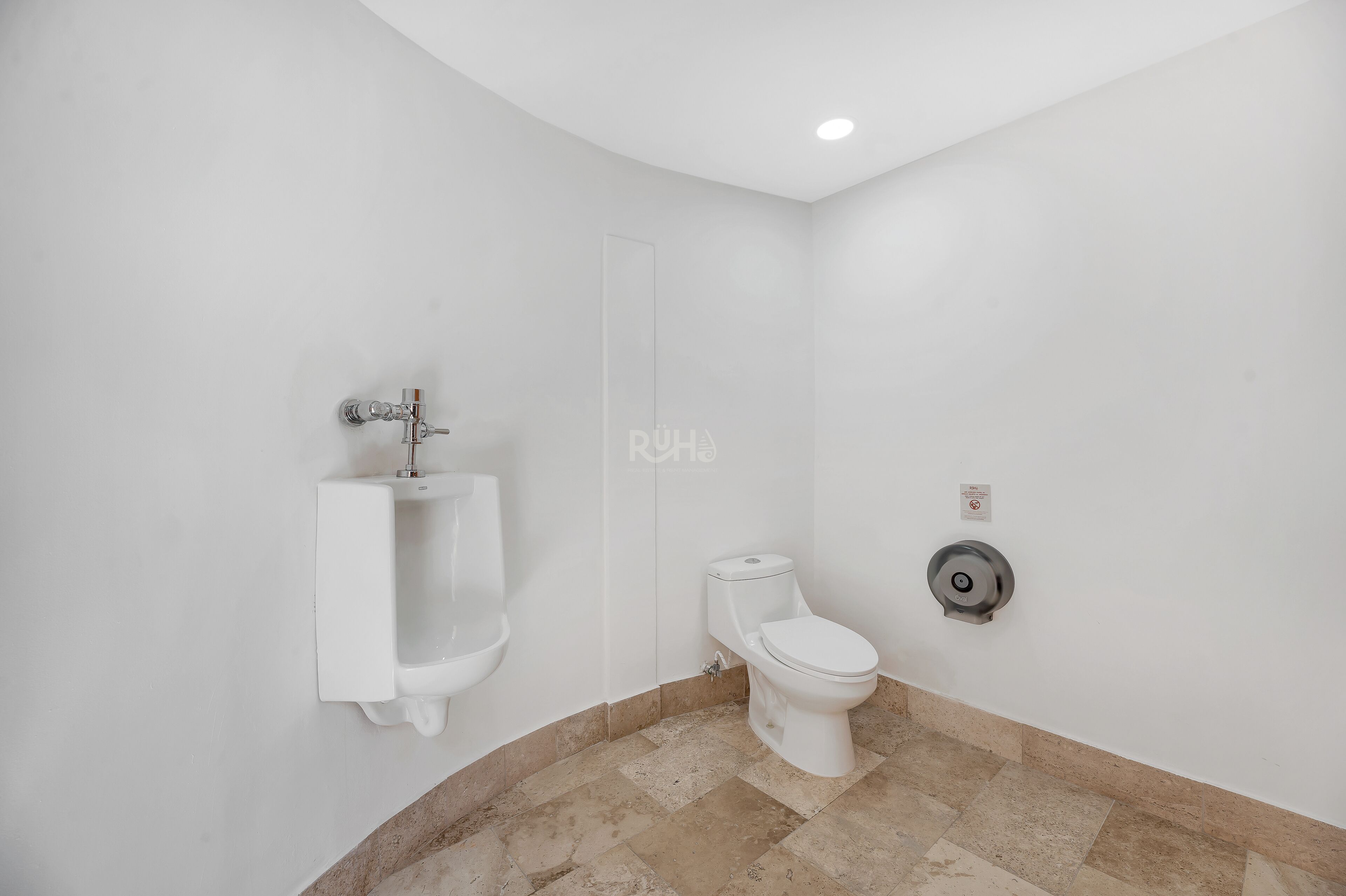 Ein Badezimmer mit Urinal, Toilette und Wandfluschtaste.