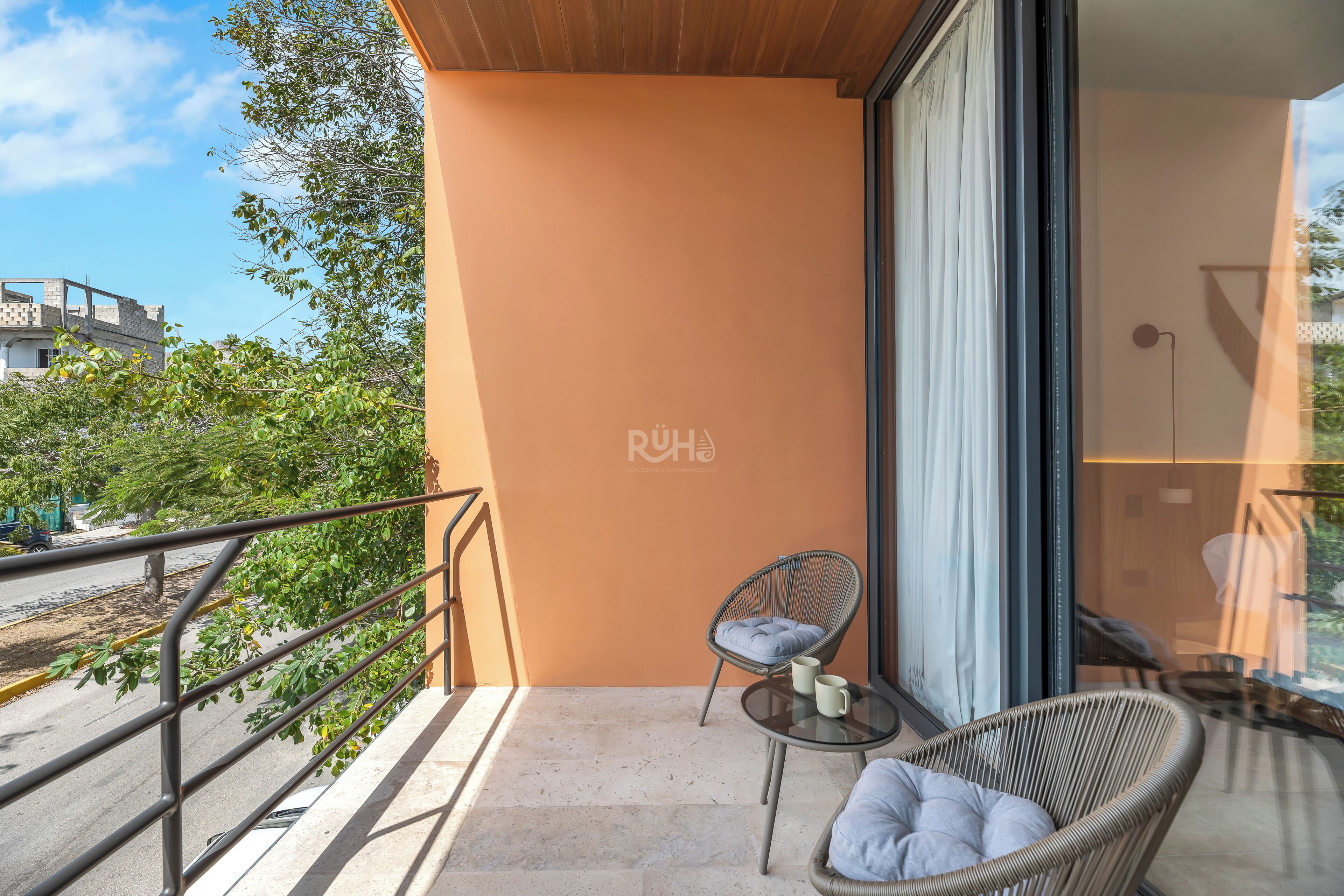 A balcony with a wicker chair, a small table, and a cushion.