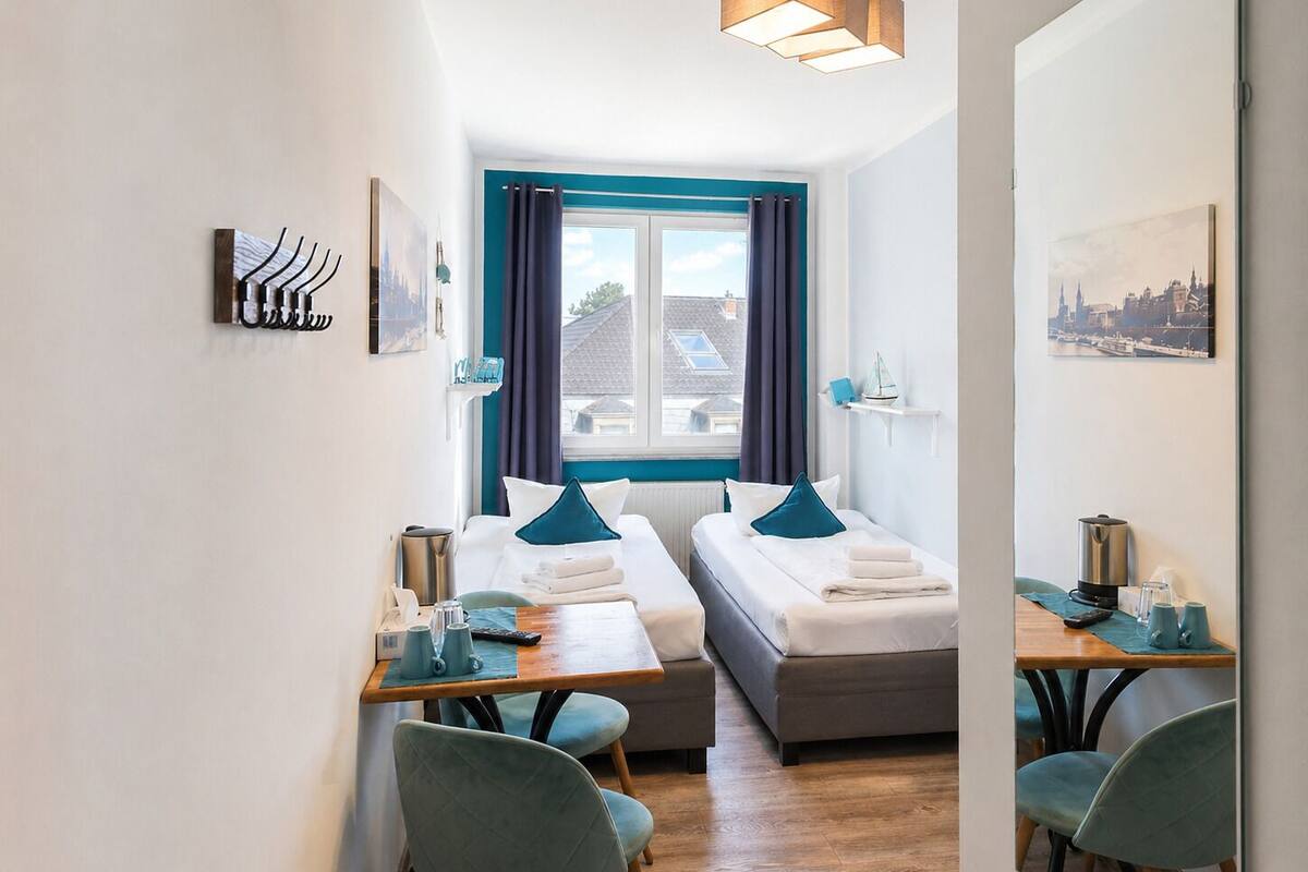 Une chambre d’hôtel avec deux lits, une table à manger, une machine à café et une vue sur la ville.