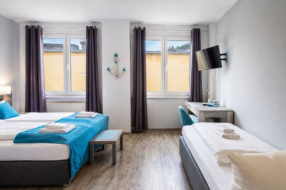 Une chambre d’hôtel avec deux lits, un bureau, une télévision et une vue sur la plage.