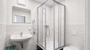 Une salle de bain moderne avec une douche à parois de verre, un lavabo et des toilettes.