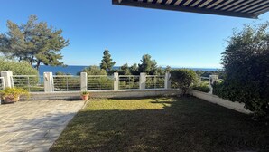 Une terrasse avec vue sur la mer, une clôture blanche et quelques plantes.