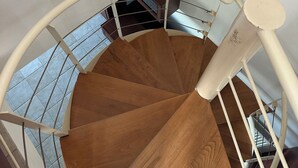 Un escalier en colimaçon avec des marches en bois et des rampes blanches.