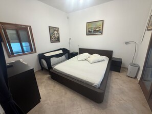 A bedroom with a bed, a desk, a lamp, and two paintings on the wall.