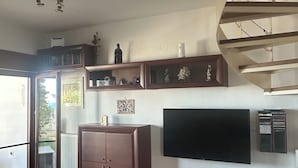 Un salon moderne doté d’un téléviseur à écran plat, d’un meuble de rangement en bois et d’un escalier.