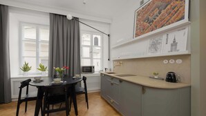 A modern kitchen with a dining table, chairs, a microwave, and a coffee maker. - Atmospheric Apartment in the New Town | Next to the Barbican (Warszawa)