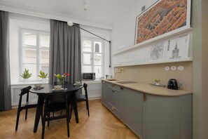 A modern kitchen with a dining table, chairs, a microwave, and a coffee maker. - Atmospheric Apartment in the New Town | Next to the Barbican (Warszawa)